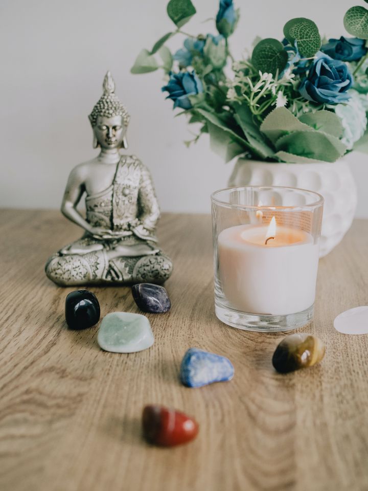 Buddha Figurine next to Crystals and Burning Candle